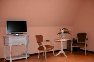 - un salon avec une télévision, une table et des chaises dans l'établissement B&B Heerlijkhyd, à Hertsberge