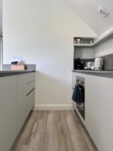 a kitchen with white cabinets and a wooden floor at The Loft Studio apartment - above detached new build garage in Llanymynech