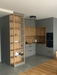 a kitchen with gray cabinets and wooden shelves at Apartament Hebanowa in Swarzędz