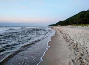 een strand met voetafdrukken in het zand en het water bij Domek nad morzem Wisełka in Wisełka