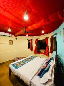 Cama en habitación con techo rojo en Sagar Guest House, en Jaisalmer