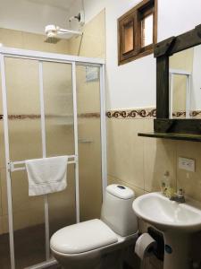 a bathroom with a shower and a toilet and a sink at Lake View Hostel in Guatapé