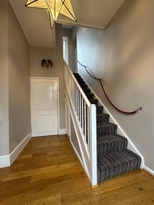 a hallway with a staircase with a chandelier at The Brontë Wing at The Apothecary Rye in Rye