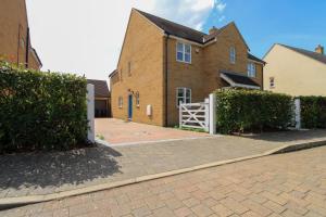 a house with a white gate and a brick driveway at Sophisticated 5-Bedroom, 3 bathroom House with Free Private Parking in Milton Keynes by HP Accommodation in Milton Keynes