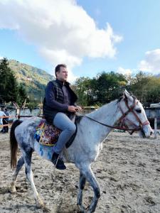 a man riding on the back of a grey horse at CİLEMONA SUİT BUNGALOWS in Ardeşen