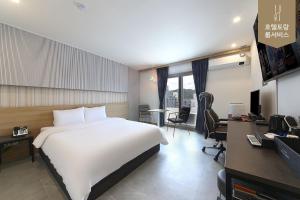 a hotel room with a large white bed and a desk at Hotel Advance Jeonju in Jeonju