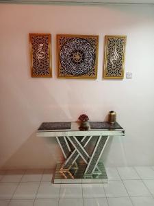 una mesa con cuatro cuadros en una pared con tres cuadros en NAURAH HOMESTAY, en Sungai Petani