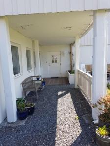 Leilighet i enebolig på Valderøya ved Ålesund في Ytterland: شرفة منزل مع مقاعد ونباتات