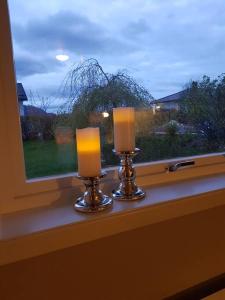 two candles sitting on a window sill in front of a window at Leilighet i enebolig på Valderøya ved Ålesund in Ytterland