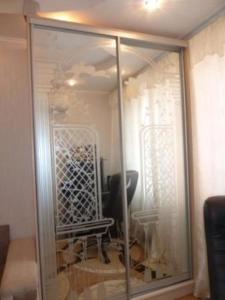 チョロノモスクにあるApartment Illichivskのガラスの仕切りと椅子が備わる客室です。