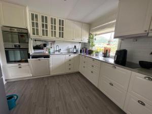 a kitchen with white cabinets and a wooden floor at Private Room With Beautiful View in Vassenden