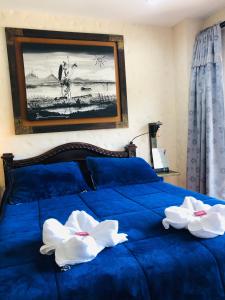 Una cama azul con dos flores blancas. en Lake View Hostel en Guatapé