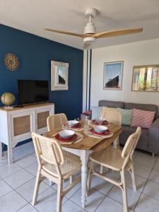 - une salle à manger avec une table, des chaises et un canapé dans l'établissement T2 rez de jardin direct plage, au Barcarès