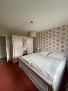 a bedroom with a large white bed with floral wallpaper at Haus-Seeschwalbe-Wohnung-3 in Nieblum
