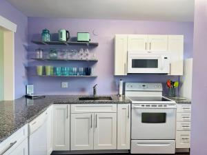 a kitchen with white appliances and purple walls at That's What Sea Said home in Holden Beach