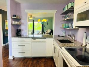 a kitchen with white cabinets and a sink at That's What Sea Said home in Holden Beach