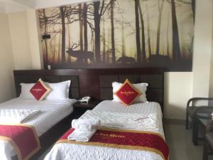two beds in a room with a painting on the wall at Hotel Nam Sơn in Lương Kê