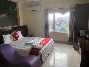a bedroom with a bed with a chair and a window at Hotel Nam Sơn An Lư in Lương Kê