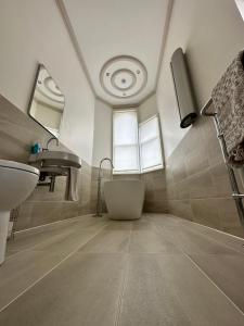 een badkamer met een bad, een wastafel en een spiegel bij Beautiful Grade II listed apartment. in Leek