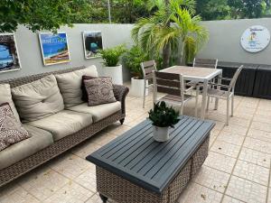 a patio with a couch and a table and chairs at Walk to the Beach 2Min, Cozy, Boutique, Pool, Palmeras Del Mar Isabela in Isabela