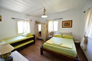 two beds in a room with two windows at Nelly's Coastal Family House in Hydra