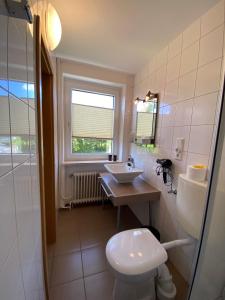 a bathroom with a toilet and a sink and a window at Buten-Diek in Dornumersiel