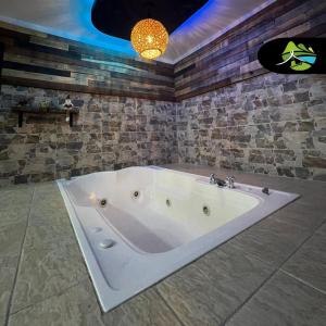a bath tub in a bathroom with a stone wall at Finca Campestre Villa del Campo in Santa Rosa de Cabal