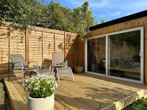 a wooden deck with chairs and a sliding glass door at Two miles from Goodwood in Tangmere