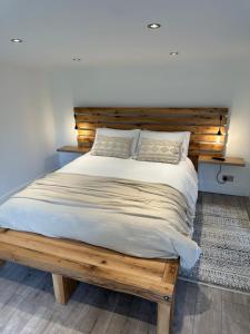 a bed with a wooden headboard in a bedroom at Two miles from Goodwood in Tangmere