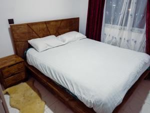 1 dormitorio con 1 cama con sábanas blancas y ventana en Greenzone Luxury 1 Bed Apartment, en Nairobi