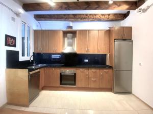 uma cozinha com armários de madeira e um frigorífico de aço inoxidável em Ramblas Waterfront Stay em Barcelona