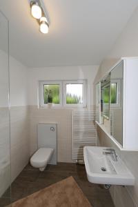 ein weißes Bad mit einem WC und einem Waschbecken in der Unterkunft Heimathafen Sillenstede in Schortens