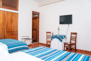 a bedroom with two beds and a flat screen tv at Casablanca Hotel in San Ramón