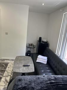 a black couch with a table in a room at Deluxe En-Suite Bedroom In the Centre of Watford in Watford