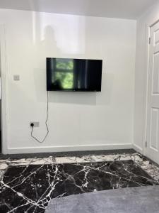 TV de pantalla plana colgada en una pared blanca en Deluxe En-Suite Bedroom In the Centre of Watford en Watford