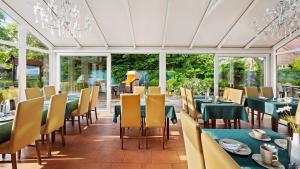 una sala da pranzo con tavoli, sedie e finestre di Hotel Deichinsel a Wangerland