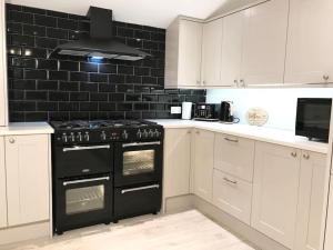 a kitchen with a black stove and white cabinets at Dolphin Retreat close to Beaches and Harbour in Poole