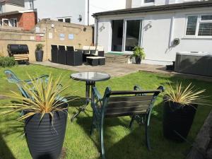 um pátio com um banco, uma mesa e vasos de plantas em Dolphin Retreat close to Beaches and Harbour em Poole