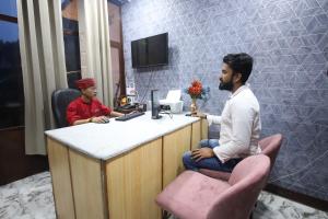 two men sitting at a counter in a barber shop at PerfectStayz Mussoorie Hills in Mussoorie