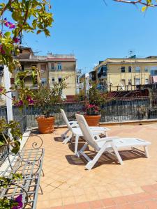 - un ensemble de chaises blanches assises sur une terrasse dans l'établissement Blessing house, à Naples