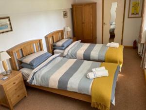 a bedroom with two beds and a night stand at Walnut Cottage in Newton Ferrers