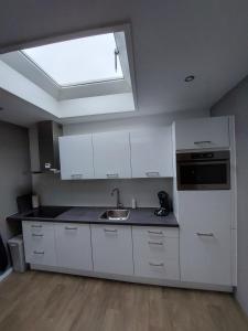 a kitchen with white cabinets and a sink and a skylight at B&Bie Ons appartement in Bad-Nieuweschans