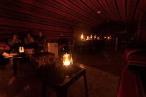 Habitación oscura con una mesa con velas. en Dana Sunset Eco Camp en Ḑānā