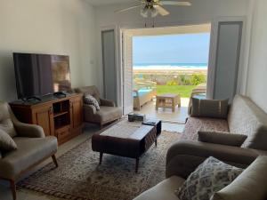 Stunning Beachfront Villa on North Coast Mediterranean في Dawwār Abū Maḩrūs: غرفة معيشة مع كنب وتلفزيون بشاشة مسطحة