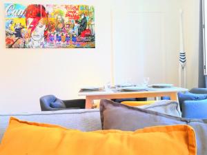 una sala de estar con sillas y una mesa con una pintura en De 2 à 6 personnes - Le Street'Art - CROISÉE DES PARCS - A 20 minutes de Center Parc et Parc Animalier Sainte-Croix - Netflix - Wifi, en Sarrebourg