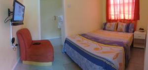 a bedroom with a bed and a chair and a television at Southern Haven Guesthouse in Laborie