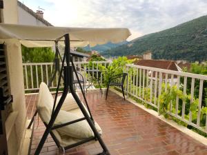 a balcony with a white umbrella and a chair at Rooms Paola in Mokošica
