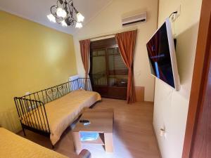 een kleine kamer met een bed en een televisie bij Pool House Stamato in Kineta