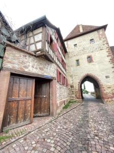 un edificio antiguo con puertas de madera y una calle de ladrillo en Le Cocon du Vignoble - Free Wifi - Netflix en Turckheim
