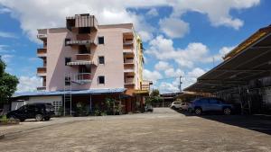 a pink building with cars parked in a parking lot at T-Bird Grand Hotel Trang ทีเบิร์ดแกรนด์ in Trang